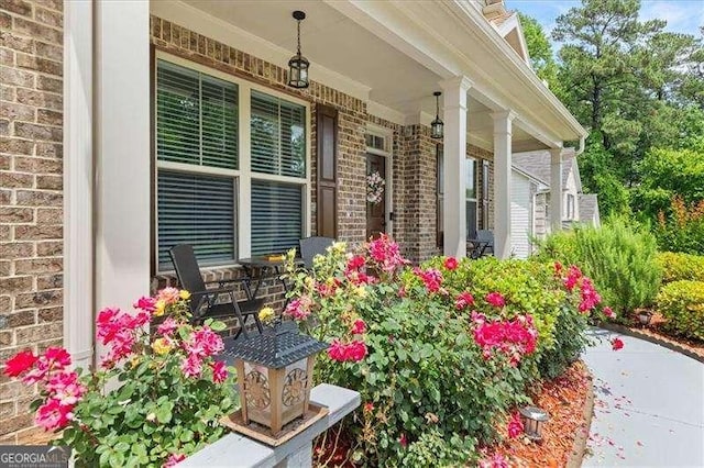 doorway to property featuring a porch and brick siding