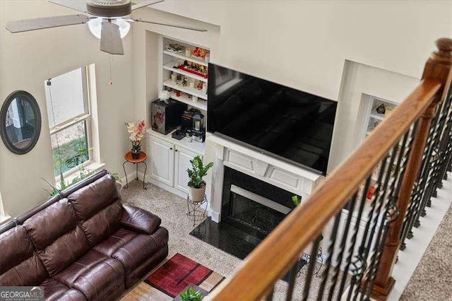 carpeted living room with a ceiling fan and a premium fireplace
