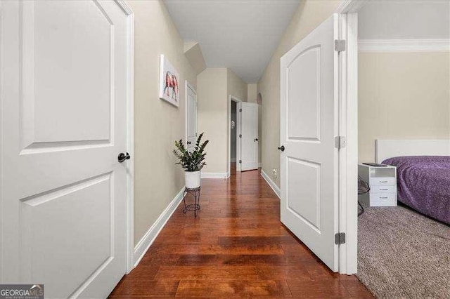 hallway featuring wood finished floors, lofted ceiling, and baseboards