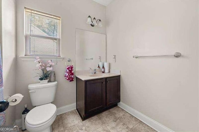 bathroom featuring baseboards, toilet, and vanity