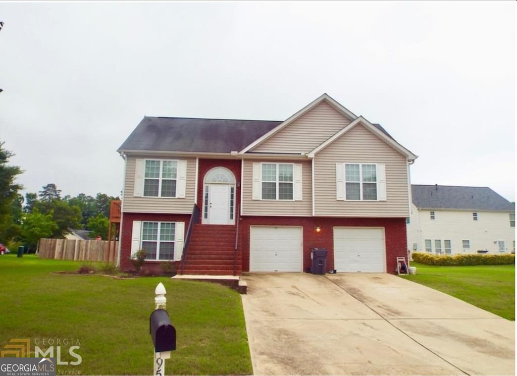 split foyer home with driveway, a garage, and brick siding