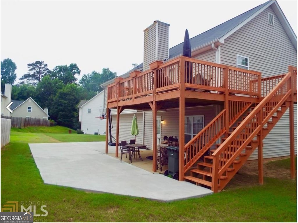 rear view of property featuring a patio area, a wooden deck, and a chimney