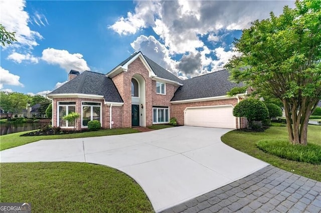 view of front of home with brick siding, a front yard, concrete driveway, an attached garage, and a chimney