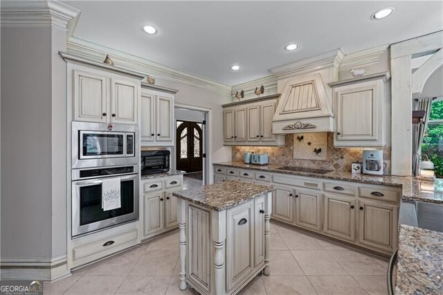 9325 Saint Georgen Cmn, Duluth, GA 30097 - kitchen with stainless steel appliances, custom range hood, tasteful backsplash, light tile patterned floors, and ornamental molding