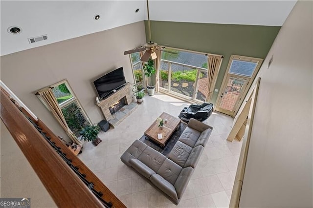 living area with high vaulted ceiling, ceiling fan, light tile patterned floors, a lit fireplace, and recessed lighting