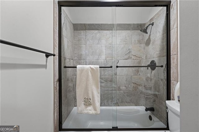 bathroom with enclosed tub / shower combo and toilet