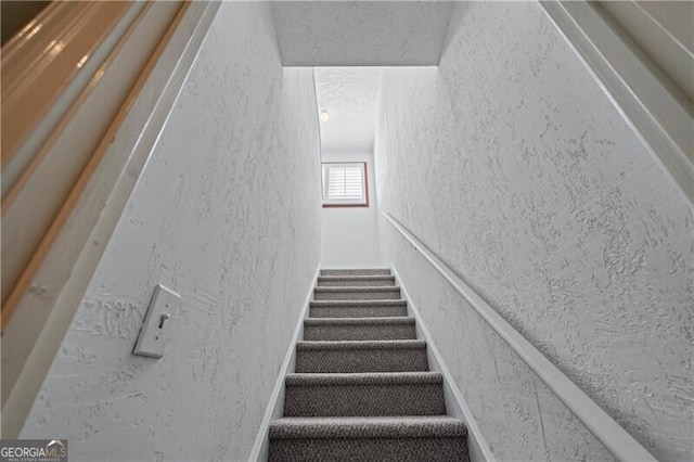 stairway with a textured wall and a textured ceiling