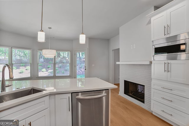 kitchen featuring stainless steel appliances, a sink, light countertops, white cabinets, and light wood-type flooring