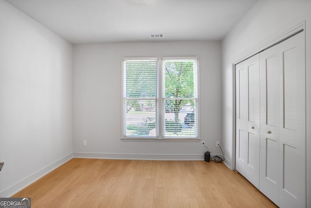 unfurnished bedroom featuring light wood-style flooring, a closet, and baseboards