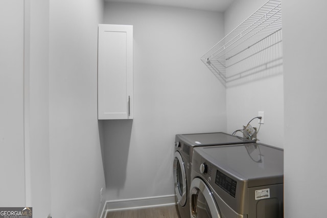 laundry room with washer and dryer, cabinet space, wood finished floors, and baseboards