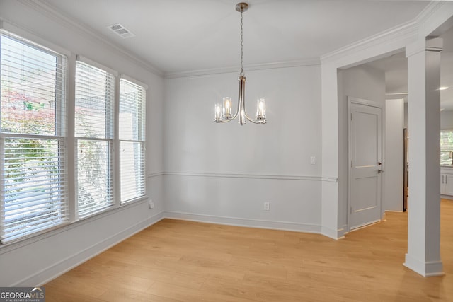 unfurnished dining area with light wood-style floors, a chandelier, baseboards, crown molding, and decorative columns