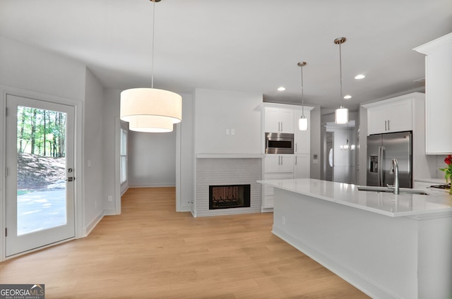 kitchen featuring appliances with stainless steel finishes, a sink, light countertops, white cabinets, and recessed lighting
