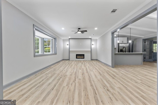 unfurnished living room with ornamental molding, light wood-type flooring, a ceiling fan, baseboards, and recessed lighting