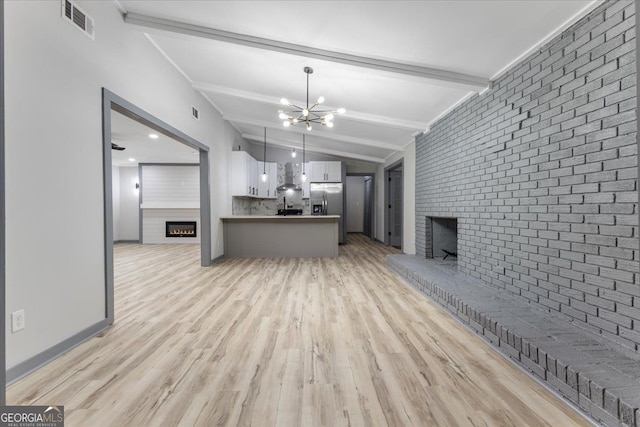 unfurnished living room featuring a brick fireplace, light wood-style flooring, a chandelier, brick wall, and baseboards