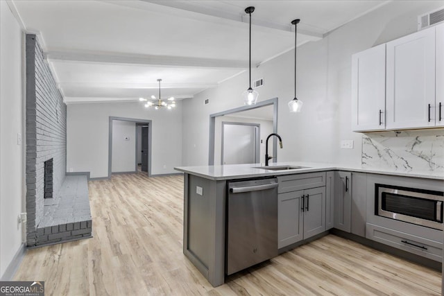 kitchen featuring stainless steel appliances, a sink, gray cabinetry, beamed ceiling, and light wood-style floors