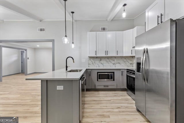 kitchen with stainless steel appliances, a sink, beamed ceiling, light wood-style flooring, and a peninsula