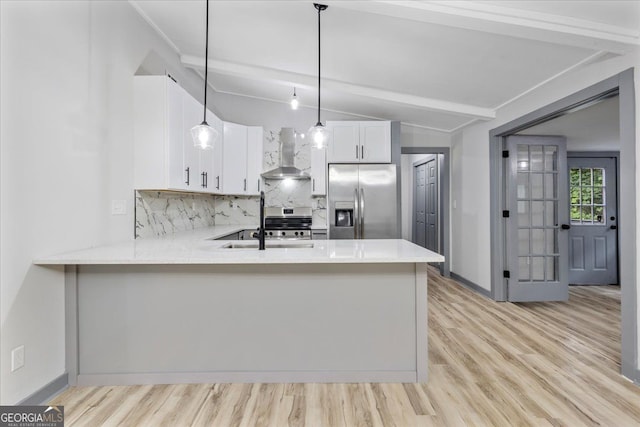 kitchen featuring stainless steel appliances, wall chimney exhaust hood, a sink, decorative backsplash, and a peninsula