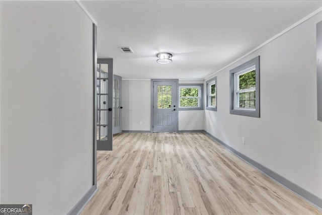 empty room with light wood-style floors, baseboards, and crown molding