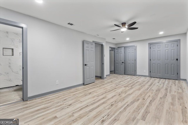 unfurnished bedroom featuring light wood-style flooring, recessed lighting, baseboards, two closets, and ensuite bathroom