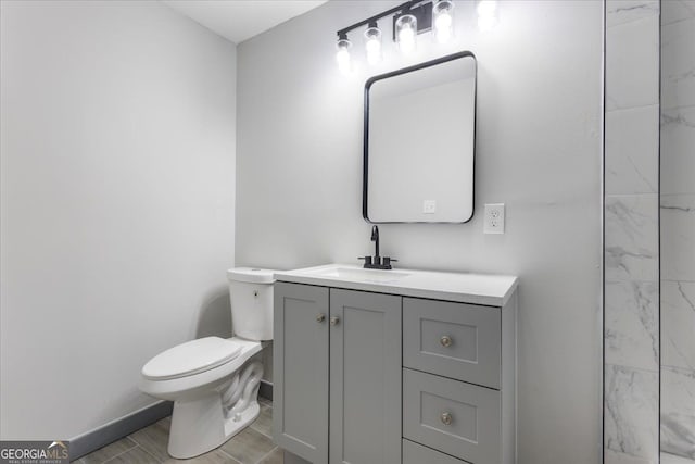 bathroom featuring toilet, vanity, baseboards, and wood finished floors
