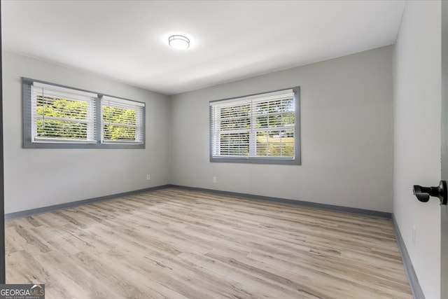 spare room with healthy amount of natural light, light wood-style floors, and baseboards