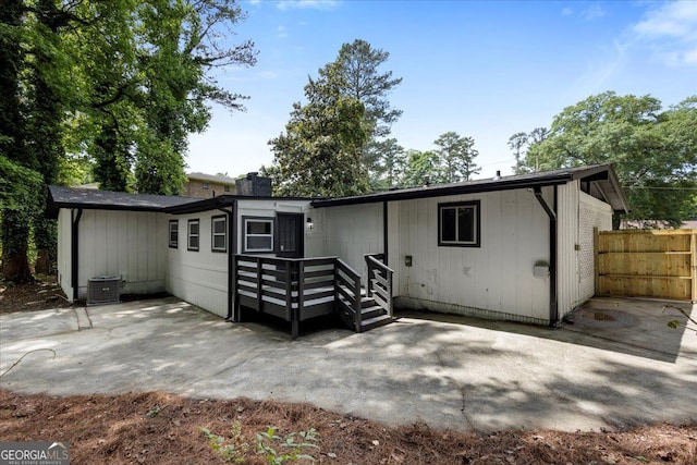 rear view of property with a patio, cooling unit, a chimney, and fence