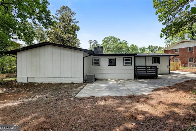 rear view of house with central air condition unit, a patio area, a chimney, and fence
