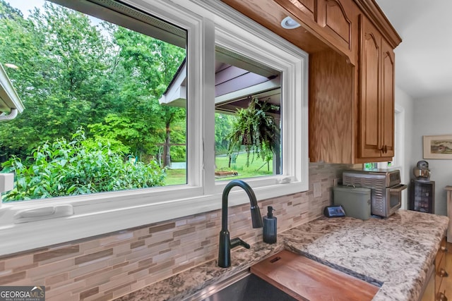 739 Rockford Creek Rd, Clarkesville, GA 30523 - kitchen view of tasteful backsplash, light stone countertops, brown cabinetry, and a sink
