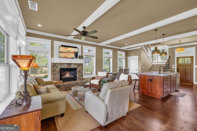 living area with stairway, a fireplace, dark wood finished floors, plenty of natural light, and beam ceiling