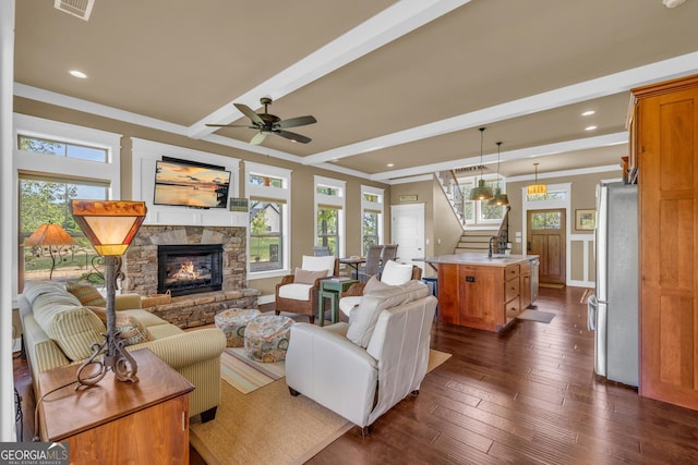 living room featuring stairs, healthy amount of natural light, a fireplace, beamed ceiling, and dark wood finished floors