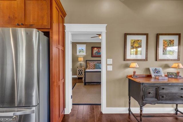 kitchen with freestanding refrigerator, baseboards, brown cabinetry, and dark wood-style flooring