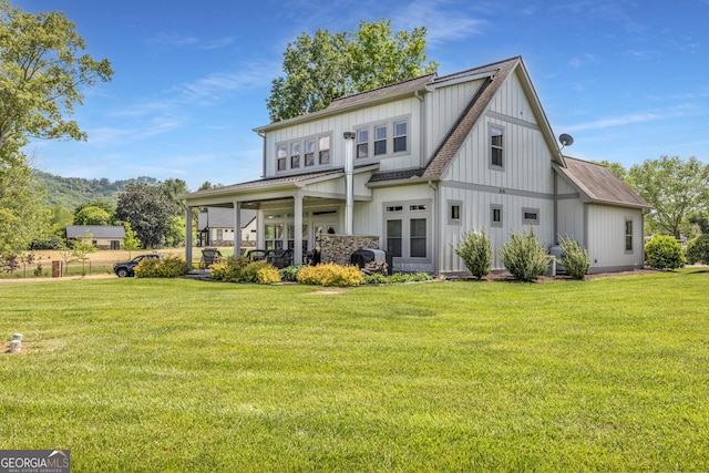 rear view of house featuring board and batten siding and a lawn