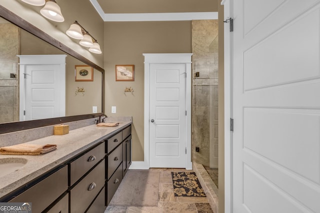 bathroom featuring a shower stall, double vanity, baseboards, stone finish floors, and crown molding