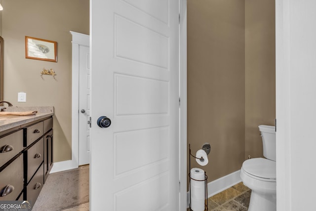 bathroom featuring baseboards, toilet, and vanity