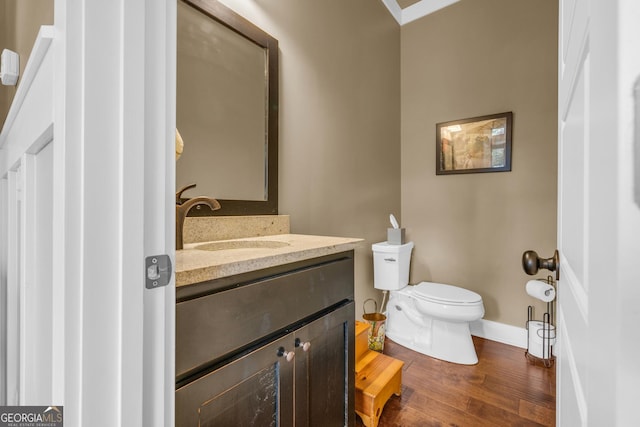 bathroom featuring toilet, baseboards, wood finished floors, and vanity
