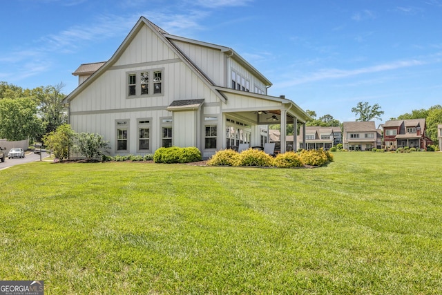 rear view of property with a lawn, board and batten siding, and ceiling fan