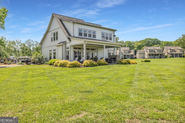 rear view of house with board and batten siding and a lawn