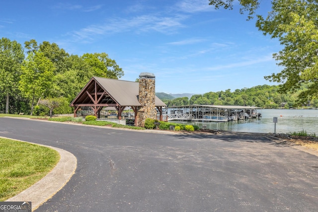 view of asphalt street with a water view and a forest view