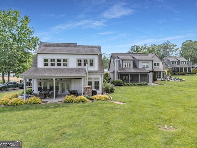 rear view of house featuring french doors, a yard, a patio, and board and batten siding