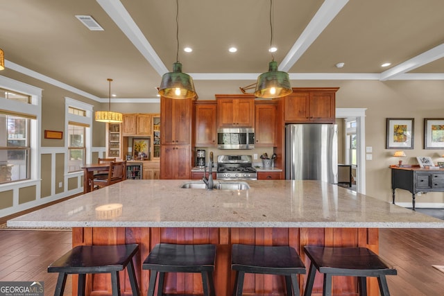 kitchen with appliances with stainless steel finishes, a sink, a spacious island, recessed lighting, and light stone counters