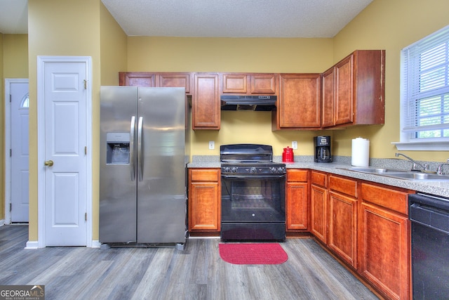 2326 Nicole Dr, Hampton, GA 30228 - kitchen featuring black appliances, a sink, wood finished floors, under cabinet range hood, and light countertops