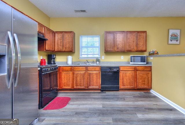 2326 Nicole Dr, Hampton, GA 30228 - kitchen featuring black appliances, under cabinet range hood, light countertops, and wood finished floors