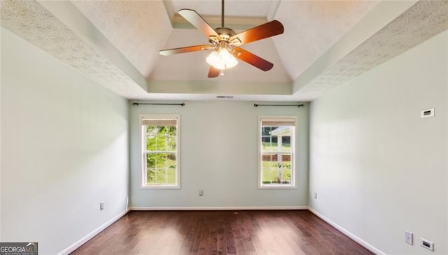 spare room with a raised ceiling, wood finished floors, ceiling fan, and baseboards