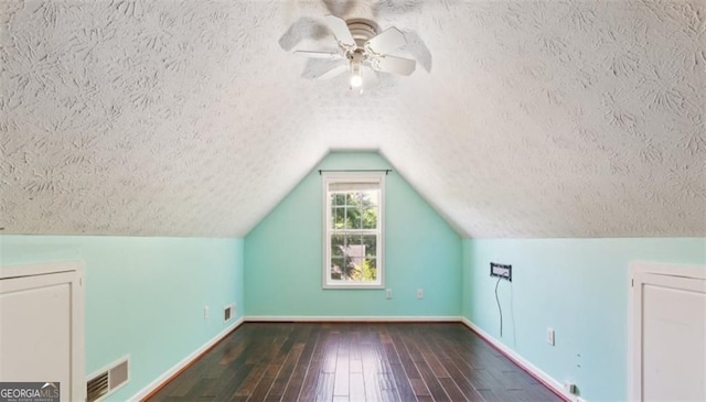additional living space with a textured ceiling, baseboards, hardwood / wood-style flooring, vaulted ceiling, and a ceiling fan