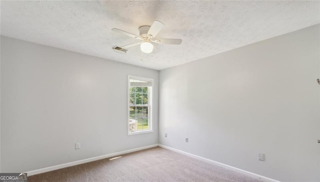 spare room with a ceiling fan, carpet, baseboards, and a textured ceiling