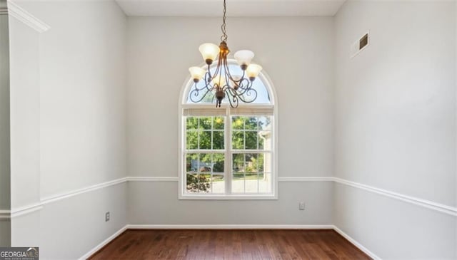 spare room with a chandelier, wood finished floors, and baseboards