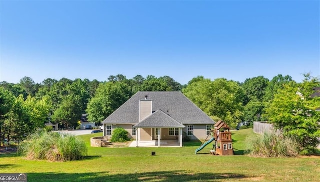 rear view of house with a playground, a patio area, and a yard