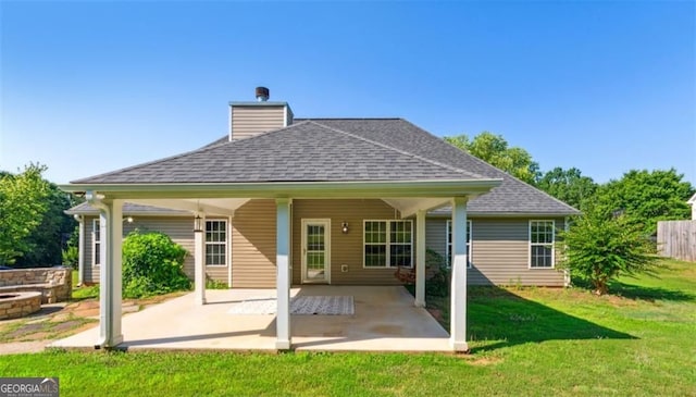 back of property featuring roof with shingles, a lawn, a patio, and a chimney