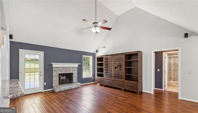 unfurnished living room with high vaulted ceiling, ceiling fan, wood finished floors, a stone fireplace, and healthy amount of natural light