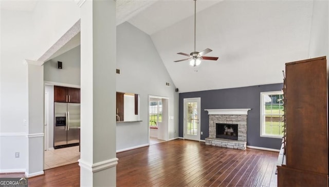 unfurnished living room featuring ceiling fan, high vaulted ceiling, dark wood-style floors, a fireplace, and baseboards